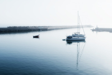 Fototapeta na wymiar Two sailing boats (yachts) and a small motor boat anchored early morning.