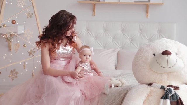 Beautiful mother with a one-year-old daughter in beautiful dresses and New Year's decor. New Year 2020.