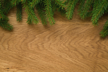 Flat lay christmas background with spruce twigs on oak wood surface