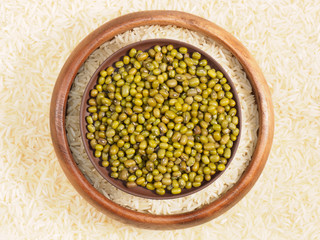 Rice in bowl and green gram in clay plate. Background from basmati rice. Indian cuisine ingredients