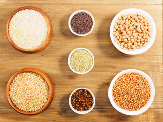 Rice, oat, mustard seeds, fennel, cloves, chick, pea, buckwheat in cups on brown wooden