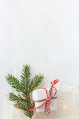 a gift in festive packaging and  spruce foot with garland. Christmas surprise on the table