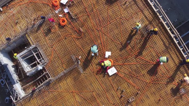 Electricians workers installing electric wires on roof of building under construction. Aerial view.
