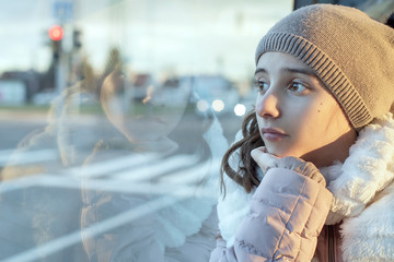 Girl teenager sits on the bus and looks out the window,teenager girl is sitting in the bus looking...