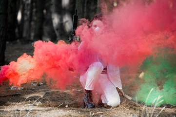 Woman in a hazmat suit wearing a respirator with dreadlocks in the woods with smoke bombs. Concept...