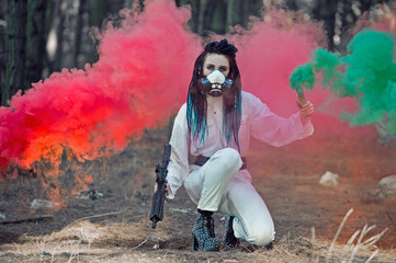 Obraz premium Woman in a hazmat suit wearing a respirator with dreadlocks in the woods with smoke bombs. Concept of radiation pollution and nuclear catastrophe. Save the planet.