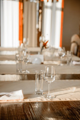 Glasses, flower fork, knife served for dinner in restaurant with cozy interior