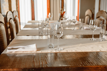 Glasses, flower fork, knife served for dinner in restaurant with cozy interior