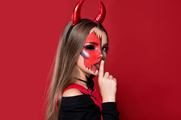 Devil. Funny imp with red horns and black bow tie at Halloween party. Halloween makeup. The devil...