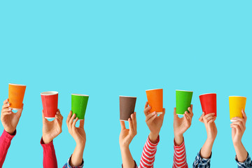 Many hands with cups for coffee on color background