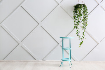 Stylish table with houseplant near grey wall
