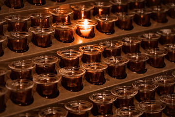 Candles in the church.Many candle flames glowing in the dark.Rows of burning candles in a dim church