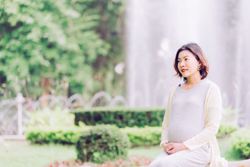 Happy pregnant woman relaxing outside in the park outdoor