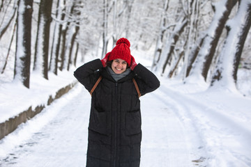 Fototapeta na wymiar young pretty smiling woman in winter coat with red hat at city forest park