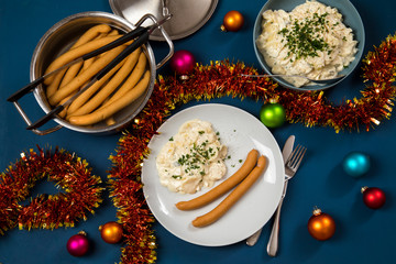 Fototapeta na wymiar Wiener Würstchen und Kartoffelsalat als typisches Weihnachtsessen zu Heiligabend in Deutschland mit bunten Weihnachtsbaumkugeln und Dekoration