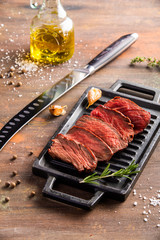 Grilled sliced beef steak with salt, garlic and rosemary on stone cutting board.