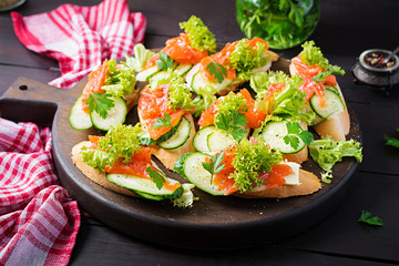 Tapas.  Salted Salmon, butter and cucumber toast sandwiches on wooden board.