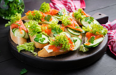 Tapas.  Salted Salmon, butter and cucumber toast sandwiches on wooden board.