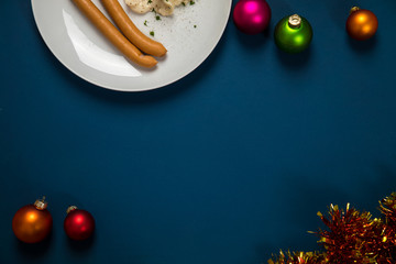 Wiener Würstchen und Kartoffelsalat als typisches Weihnachtsessen zu Heiligabend in Deutschland mit bunten Weihnachtsbaumkugeln und Dekoration