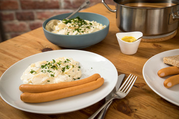 Wiener Würstchen im Topf, Senf und  Norddeutscher Kartoffelsalat mit Mayonnaise, Ei und Gurke als Mahlzeit auf Holz Tisch