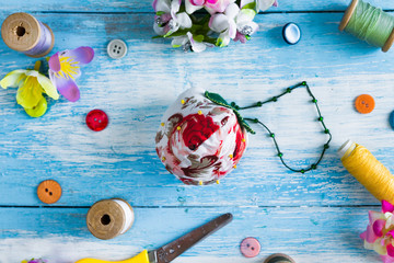 Handmade and needlework. Pin cushion with a simple ornament and sewing supplies. Top view. Blue wooden background