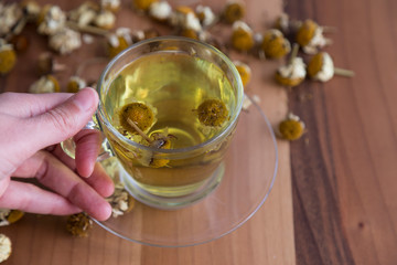 the cup of daisy tea on the wooden background.