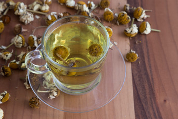 the cup of daisy tea on the wooden background.