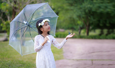 Little Asian girl holding clear umbrella and smiling with happiness select focus shallow depth of field