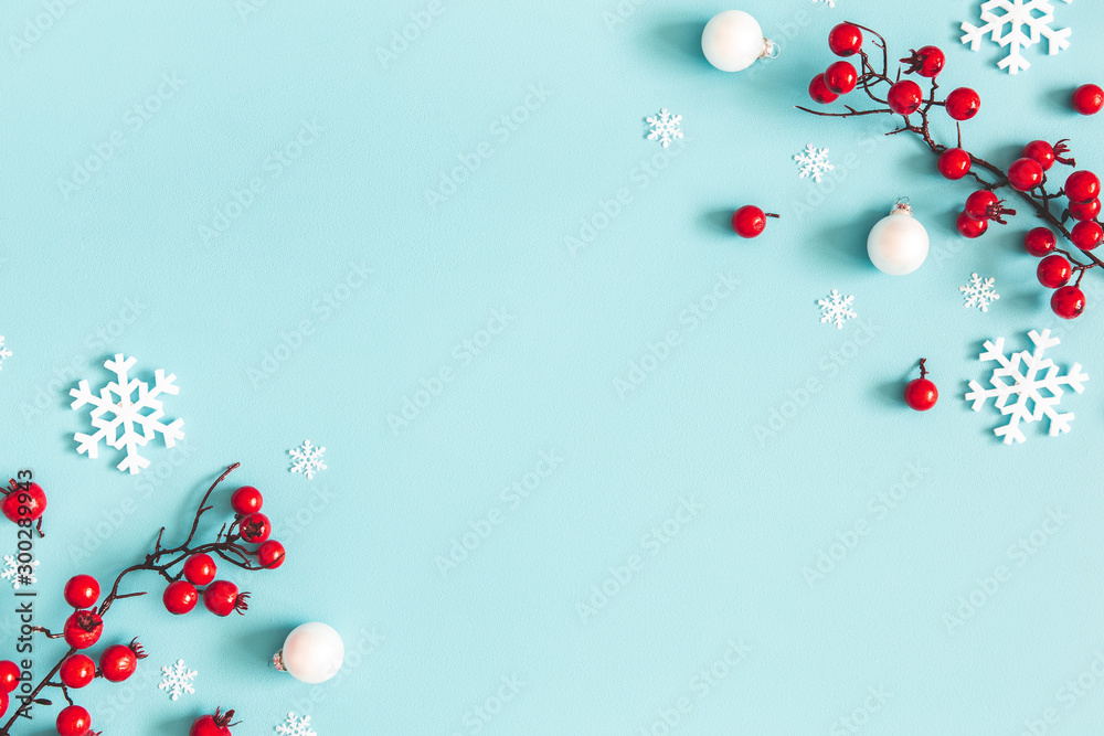 Wall mural Christmas or winter composition. Snowflakes and red berries on blue background. Christmas, winter, new year concept. Flat lay, top view, copy space