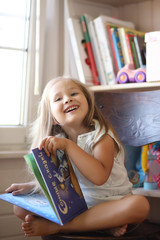 Beautiful girl sitting on a sofa and reading a book