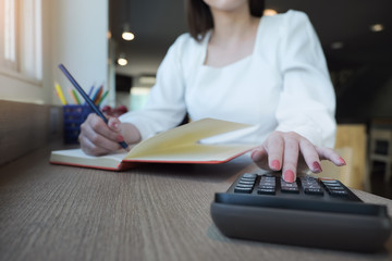 Fototapeta premium woman working with finance calculate on calculator and using notebook in office room.
