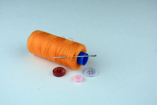Orange Spool Of Thread With A Needle And Buttons