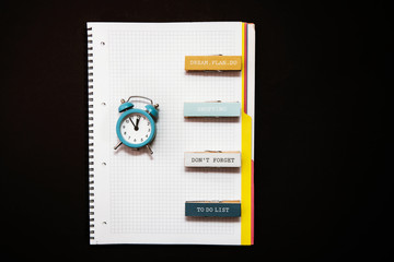 Blue alarm clock, clean open notebook diary.