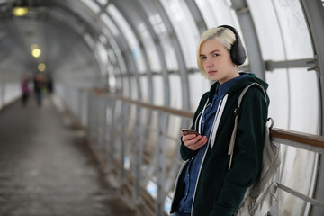 Naklejka na ściany i meble Young girl listens to music in big headphones in the subway