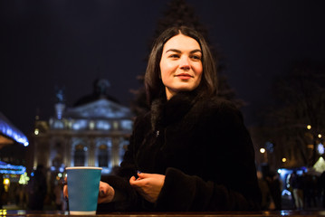 A beautiful young girl drinks hot coffee at Christmas fair. Concept Lifestyle, Urban, Winter, Vacation