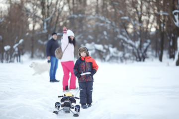 Happy family mom, dad and son walk in the woods. Winter tourism. Family sport. Walking with your dog in winter park