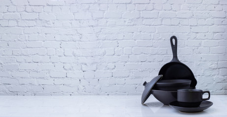 Black kitchenware on white brick wall texture background.