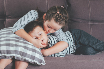 Cute little girl kissing his brother. Kids playing on sofa. Children with small age difference.