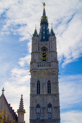 Vertical picture using backlighting of the tower of the Belfry (Het Belfort) of Ghent taken from Botermarkt, in Belgium, Europe, during a sunny day. Tallest bell tower in Belgium with 91-meters high