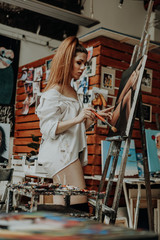 Obraz na płótnie Canvas Portrait of female artist with brush in art workshop