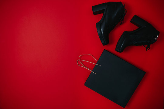 Black friday image with space for text. Bkack friday sale flat lay. Black friday bag and black boots on the red background. Shopping banner.