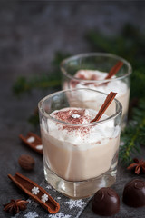 Eggnog in glass cups with a delicate foam, spices and a cinnamon stick