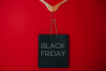 Black friday image with space for text. Bkack friday sale flat lay. Black friday bag. Hangers on the red background.