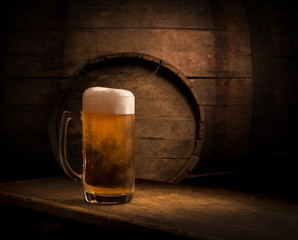 Oktoberfest beer barrel and beer glasses with wheat and hops on wooden table