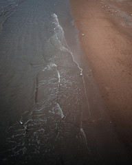 Waves crashing into a sandy beach, dark moody summer photo