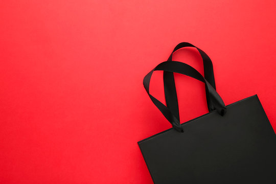 Black shopping bag on a red background.