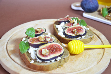 Sandwiches with ricotta, fresh figs, walnuts and honey. Canape or crostini with toasted baguette, cheese, jam, Delicious appetizer, ideal as an aperitif. Selective focus