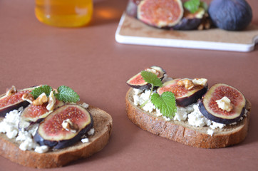 Sandwiches with ricotta, fresh figs, walnuts and honey. Canape or crostini with toasted baguette, cheese, jam, Delicious appetizer, ideal as an aperitif. Selective focus