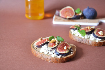 Sandwiches with ricotta, fresh figs, walnuts and honey. Canape or crostini with toasted baguette, cheese, jam, Delicious appetizer, ideal as an aperitif. Selective focus