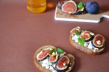 Sandwiches with ricotta, fresh figs, walnuts and honey. Canape or crostini with toasted baguette, cheese, jam, Delicious appetizer, ideal as an aperitif. Selective focus